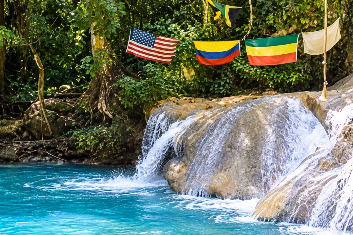 Small waterfall into a turquoise pool with flags hung above at Blue Hole