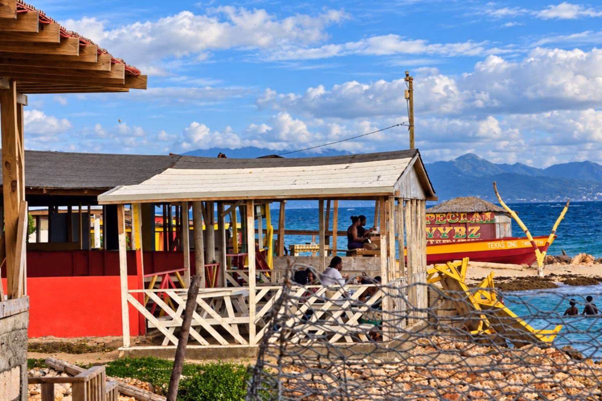 Fish shacks by the sea at Hellshire Beach with hills across the water