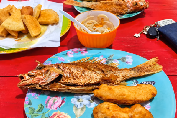 Fried fish with festival and bammy on colorful plates at Hellshire Beach