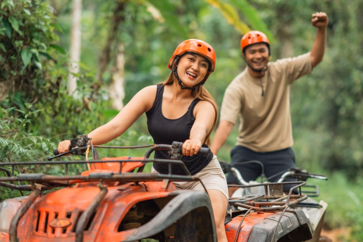 Two riders in orange helmets on ATVs along a forest trail at Chukka Sandy Bay