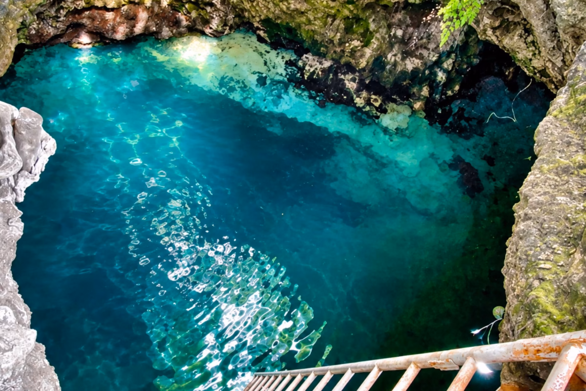 Turquoise water in the cliff-sided Blue Hole in Negril, seen from the ladder