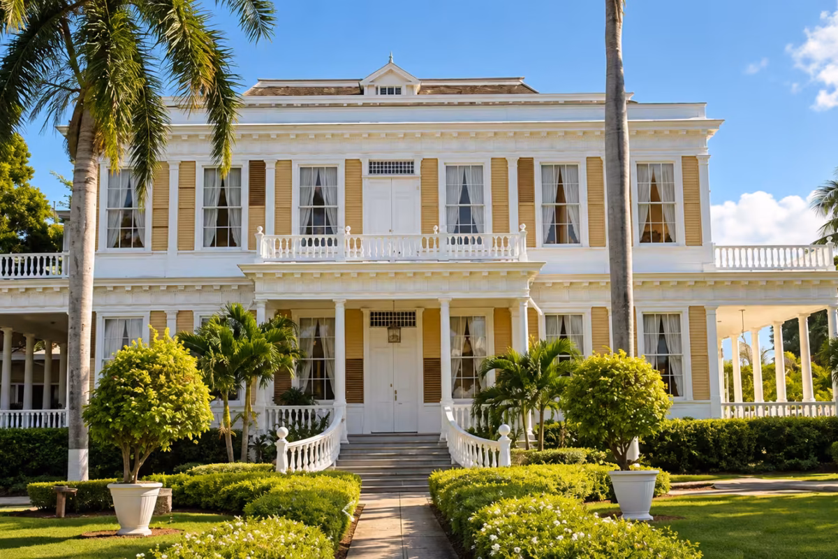 Cream colonial-style mansion with white verandas, palm trees and trimmed hedges