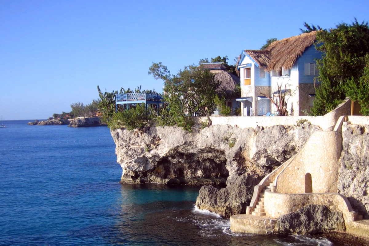 Cliffside cottages and carved stone steps above deep blue water in Negril's West End
